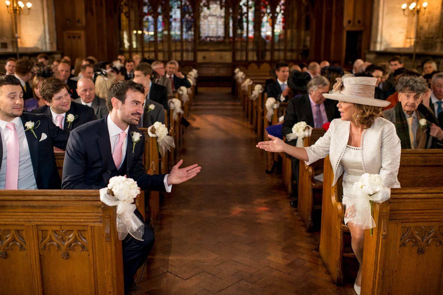 groom talking with mother of the bride across the aisle at St Etheldredas church