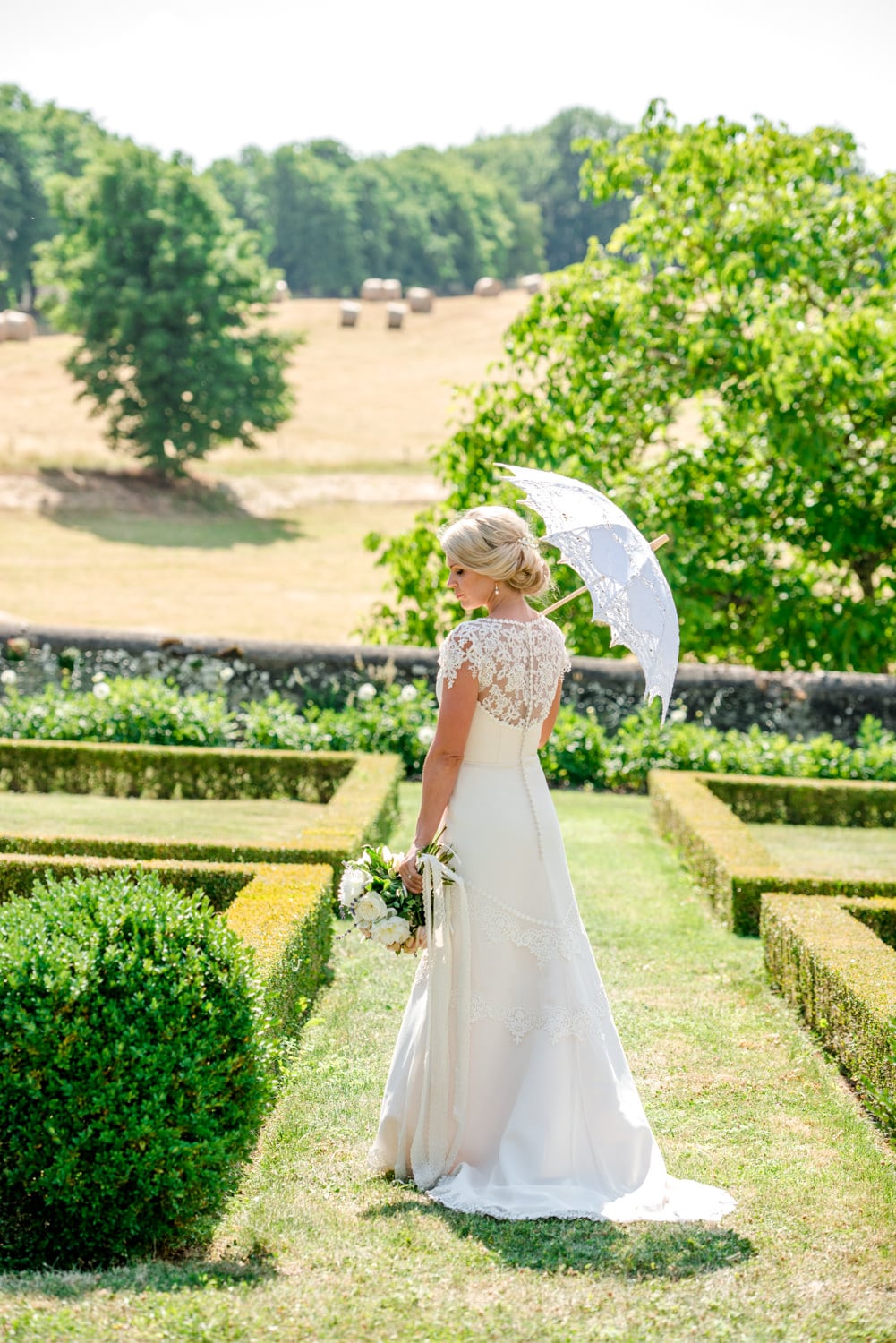 portrait of bride with parasol in gardens of Chateau de Lacoste wedding venue