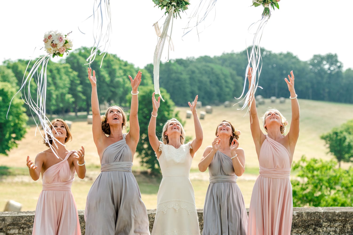 bride and bridesmaids throwing their bouquets at Chateau de Lacoste wedding venue