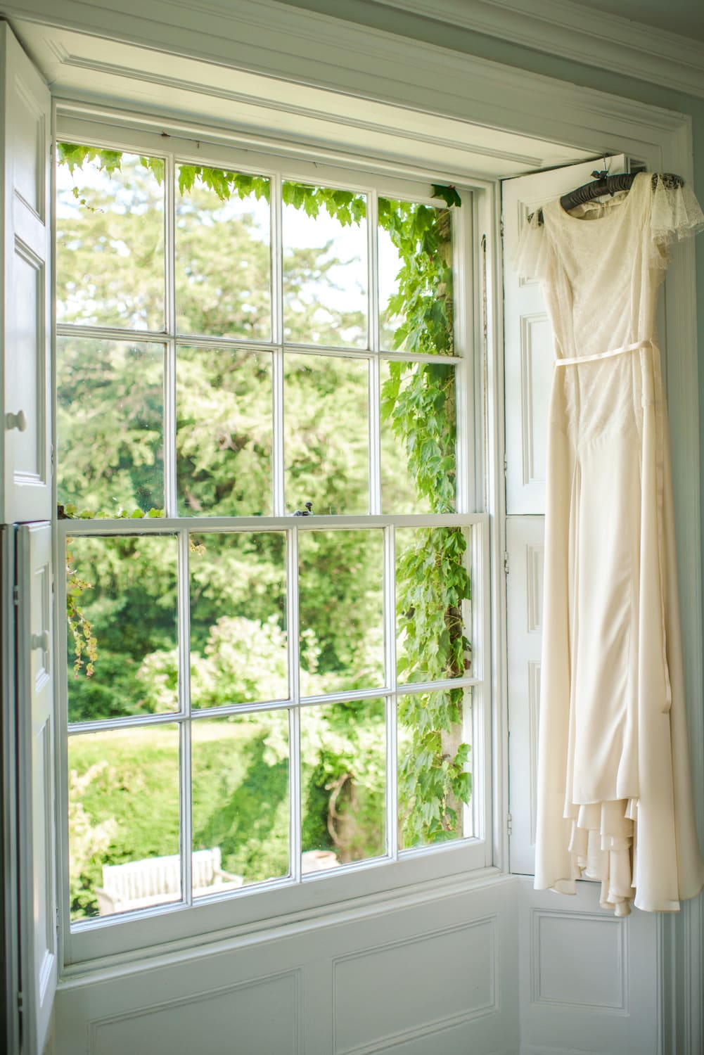 wedding dress hanging next to sash windows