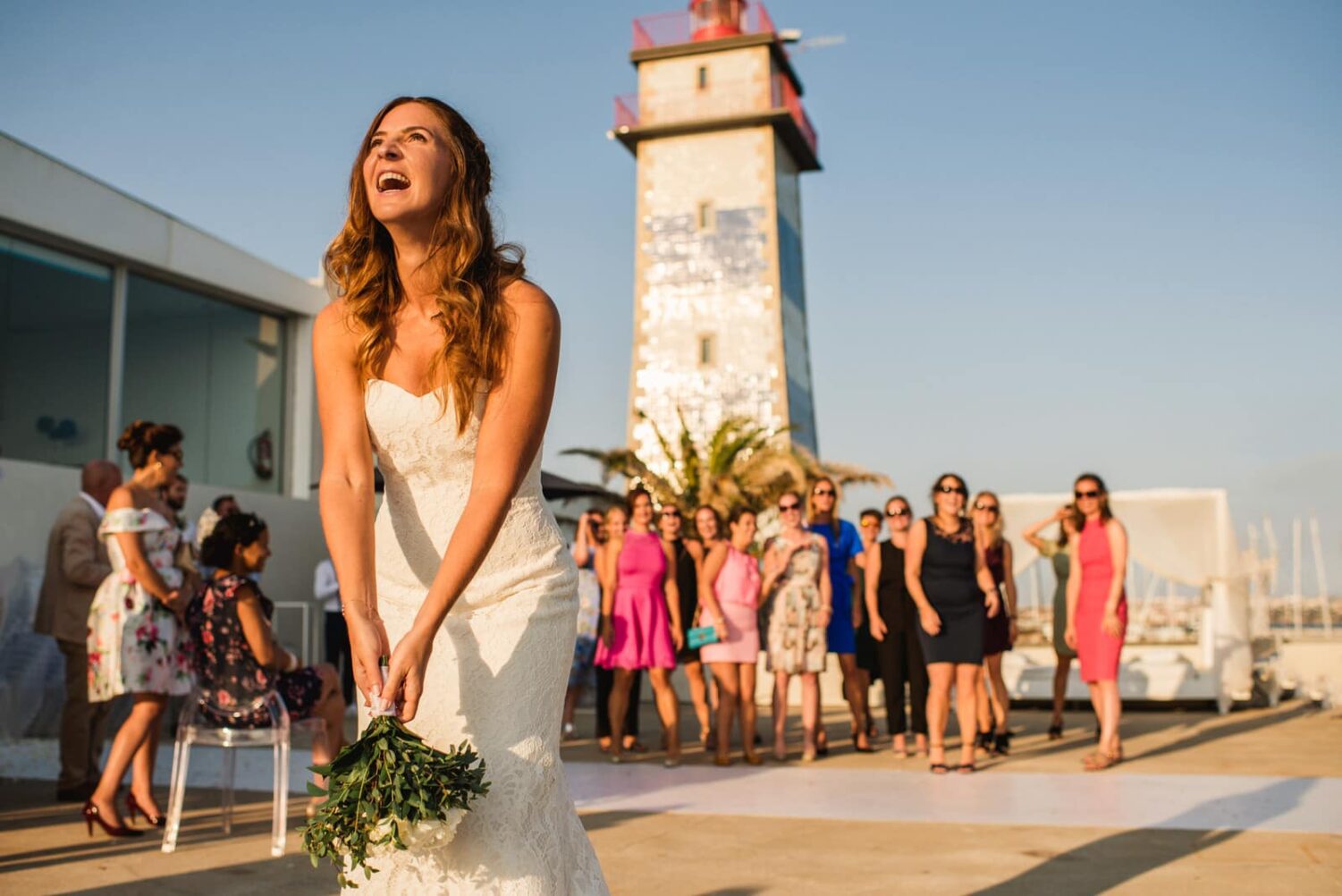 bride throwing bouquet by a lighthouse