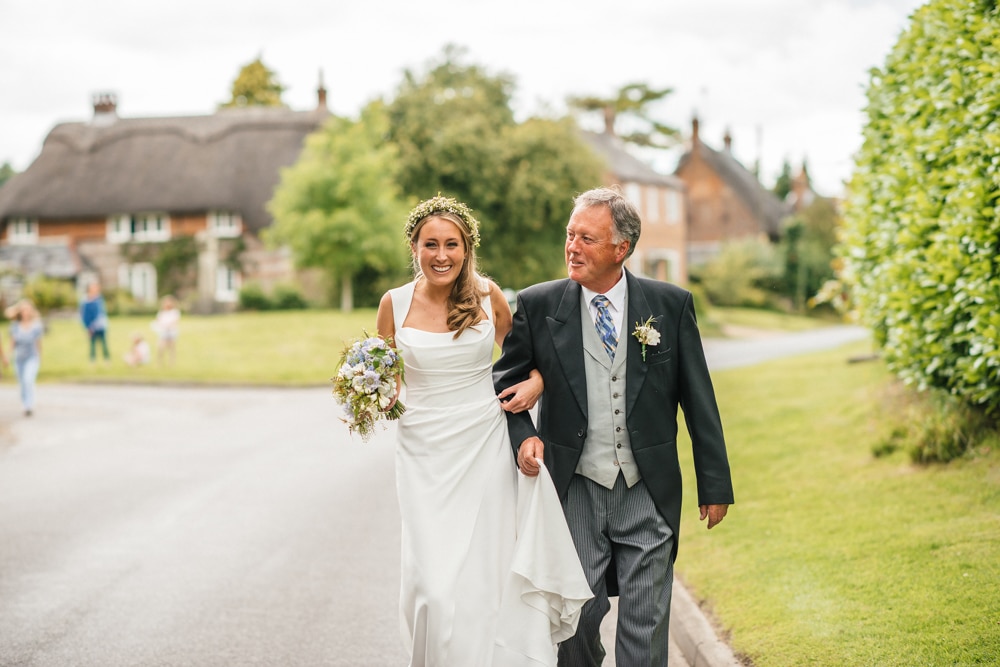 father of the bride walking his daughter to the church through village