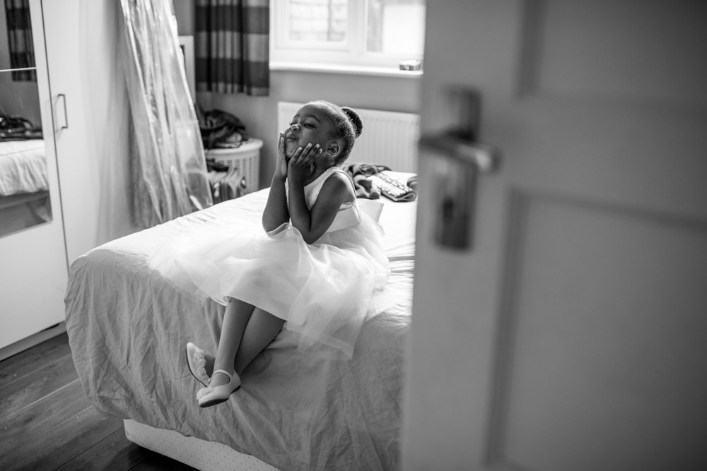 flower girl on bed pulling silly faces