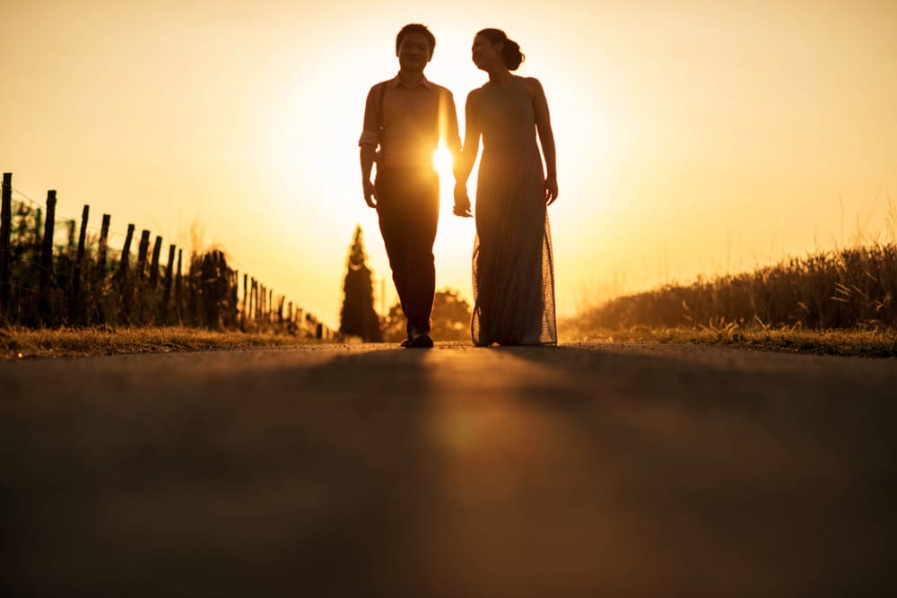 bride and groom holding hands walking towards camera during sunset