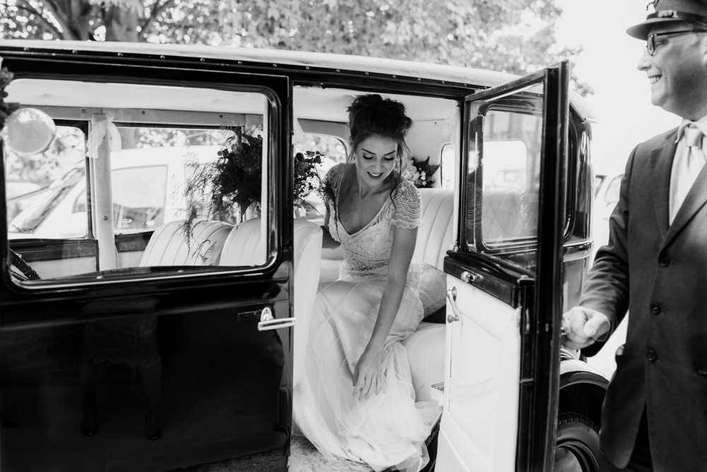 bride getting out vintage wedding car