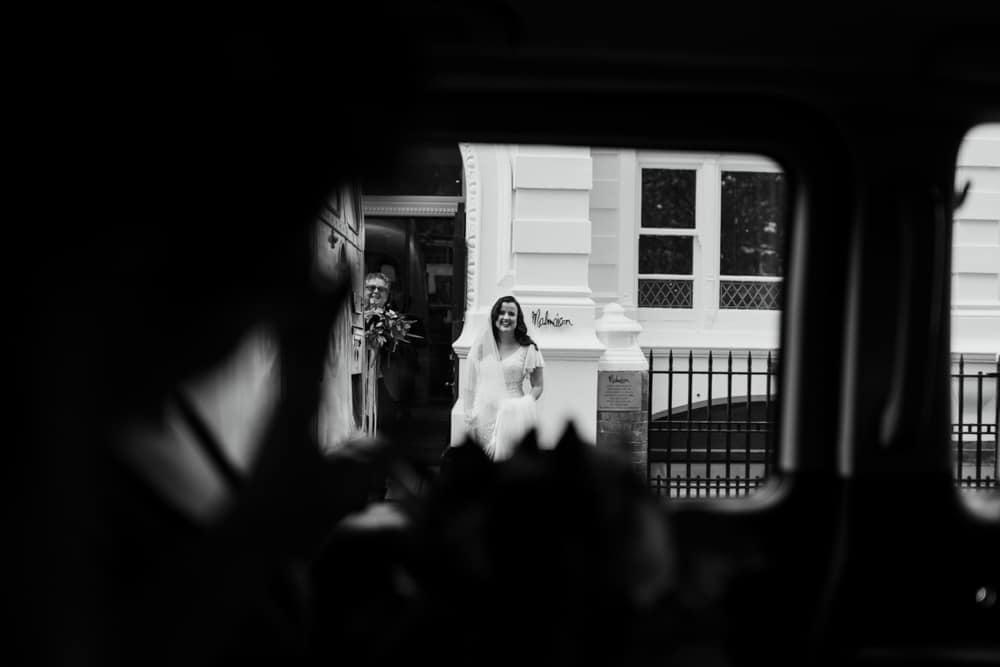 bride photographed through taxi door