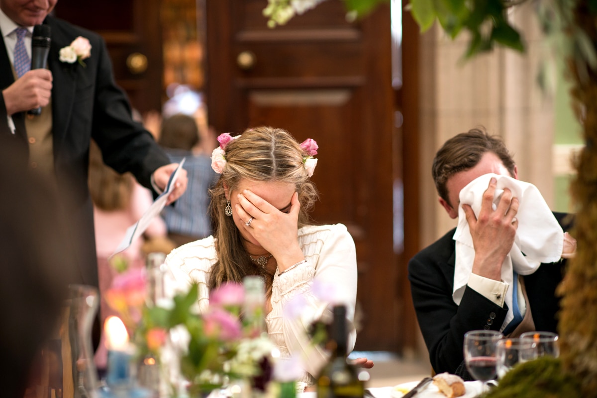 bride and groom hiding their faces in embarrassment during the speeches