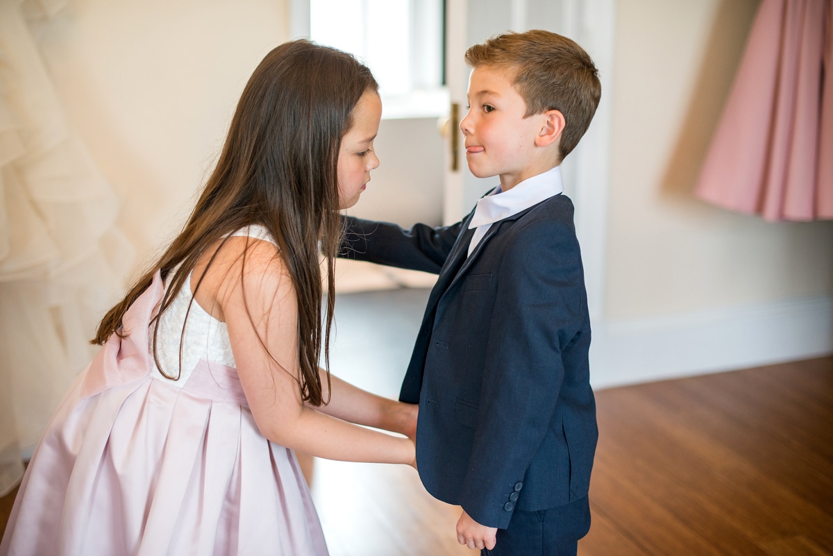 pageboy receiving help dressing from flower girl