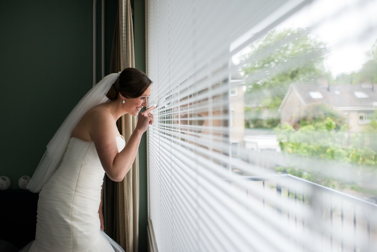 bride looking out of window at groom arriving