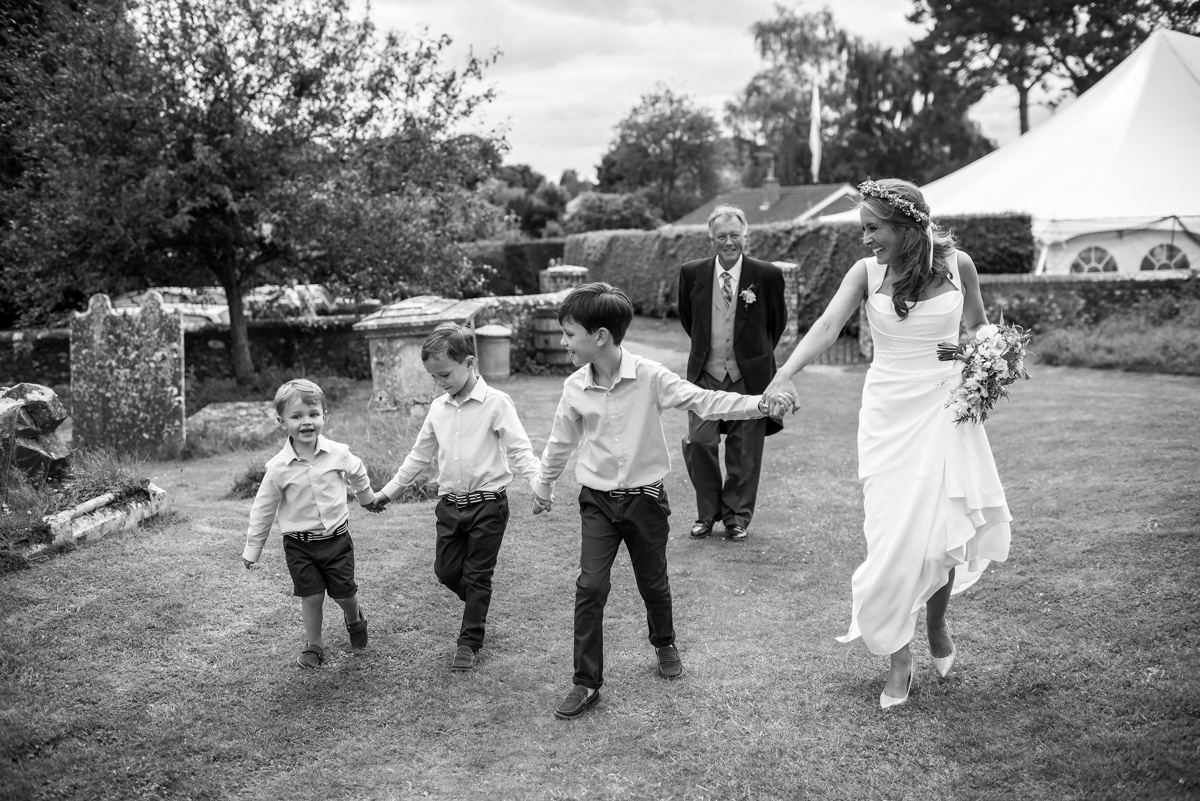 Bride walking to church with 3 pageboys