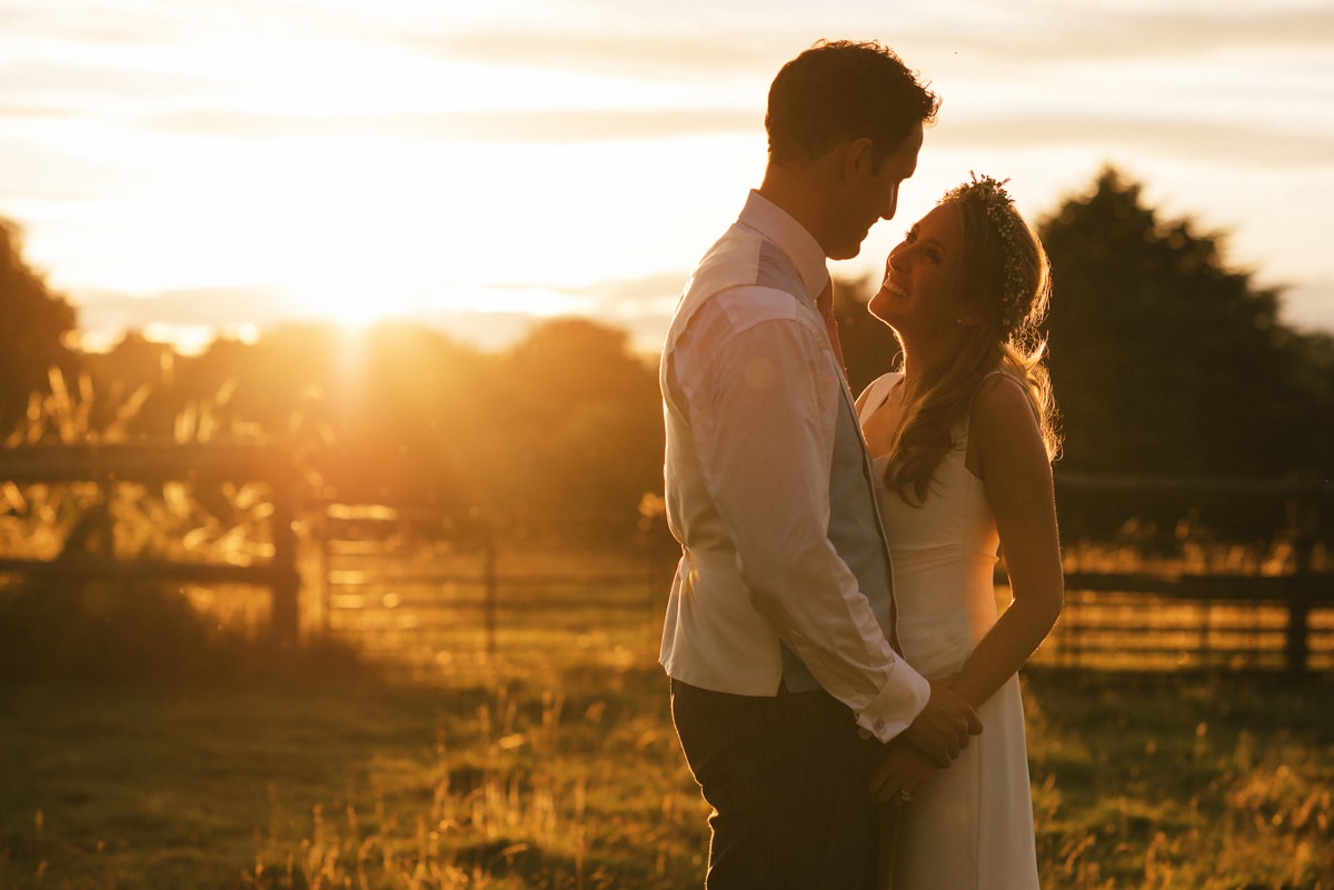 Golden light portrait of bride and groom in field