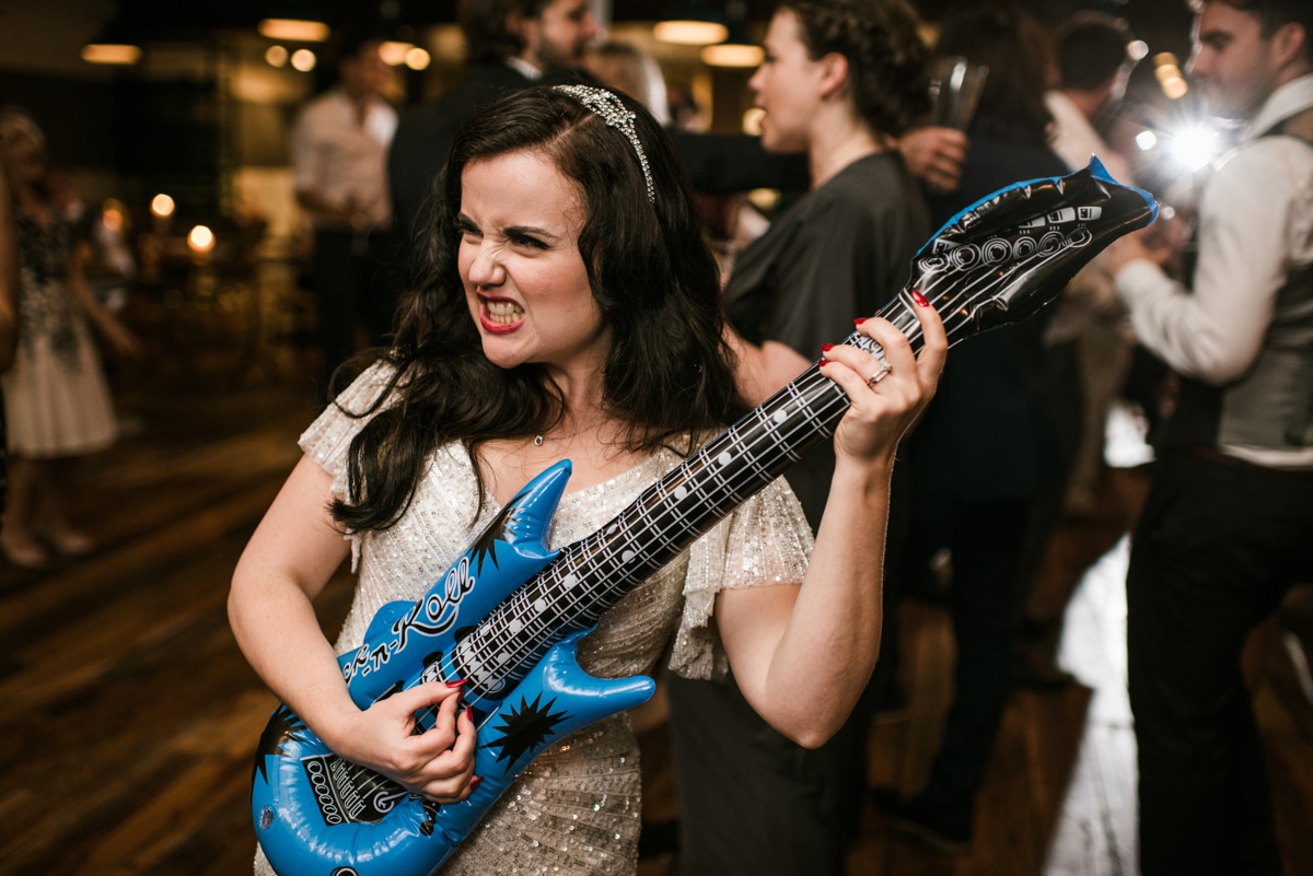 bride playing a blow up guitar, London wedding at the Happenstance