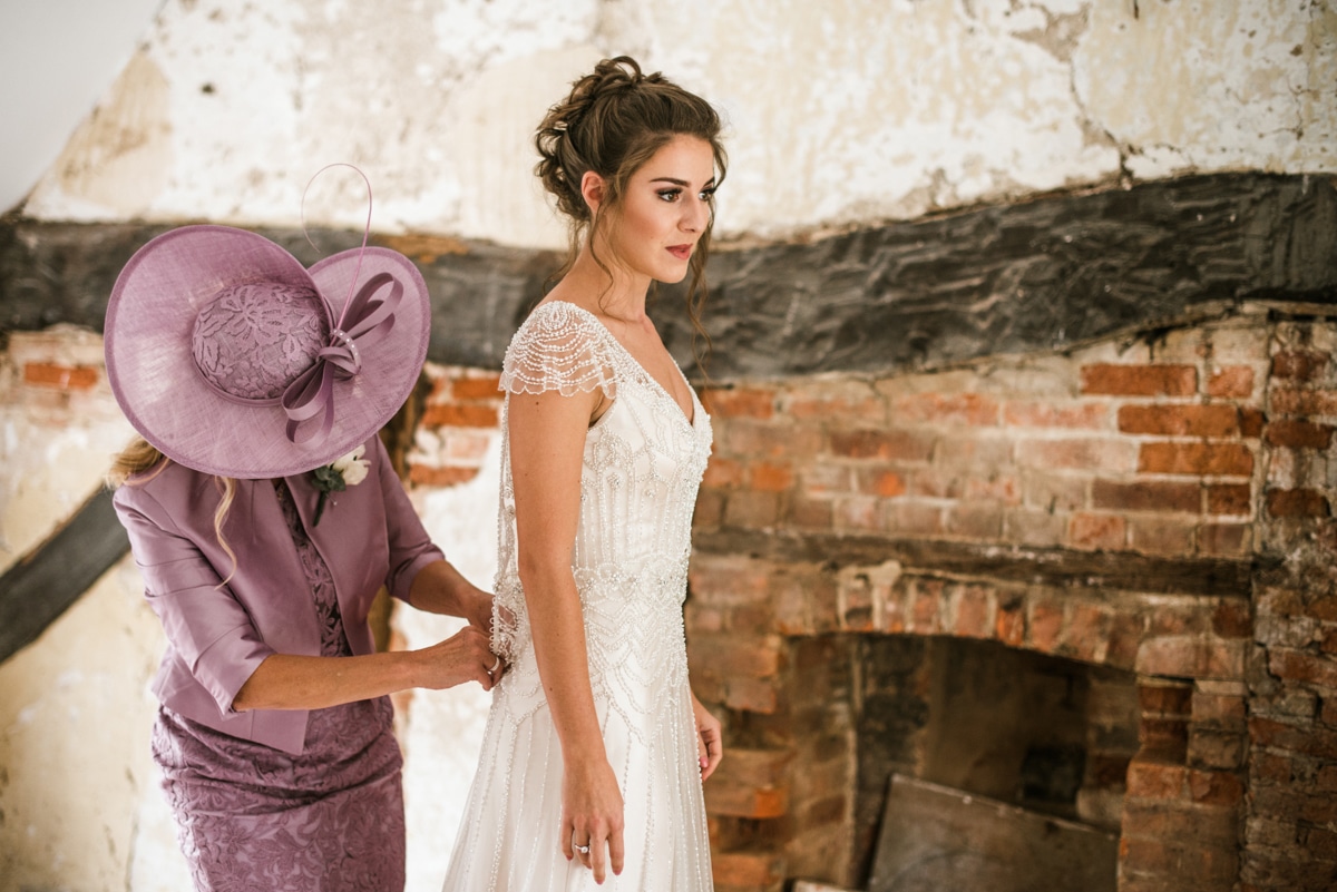 mother helping bride into wedding dress