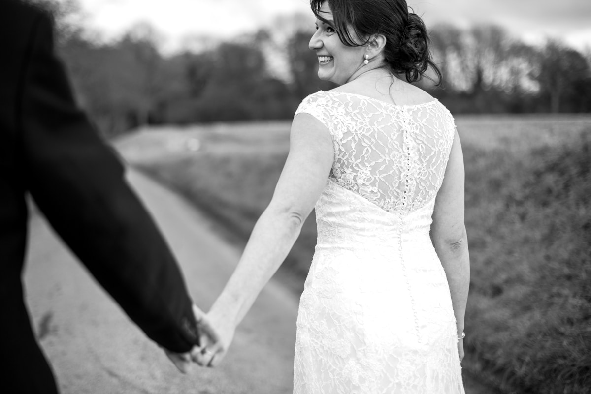 Bride and groom holding hands walking away from camera