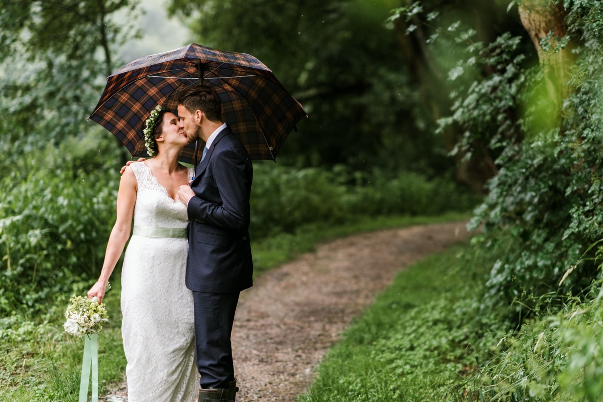 bride and groom kissing under umbrella