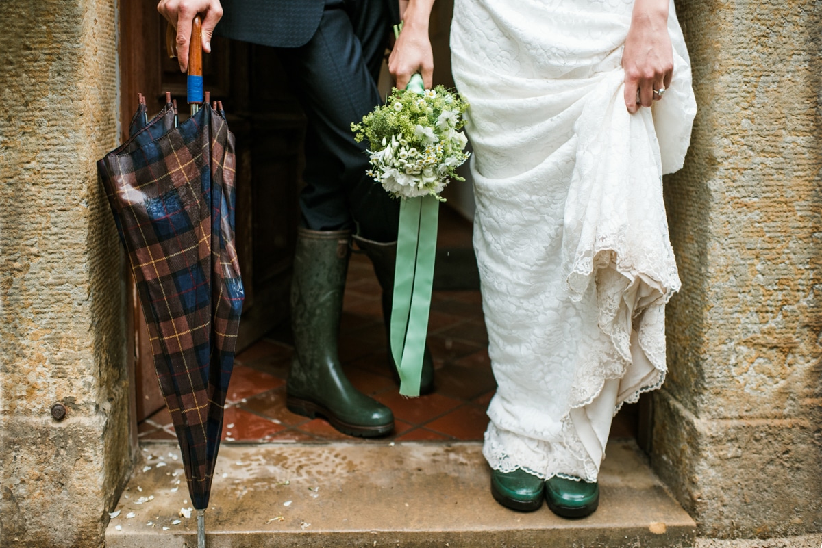 Bride and groom wearing wellies and holding umbrellas, wet wedding