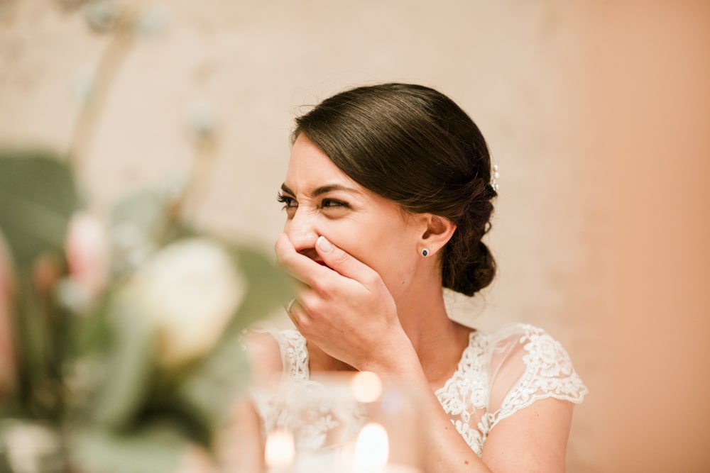 bride laughing with hand over her mouth at wedding