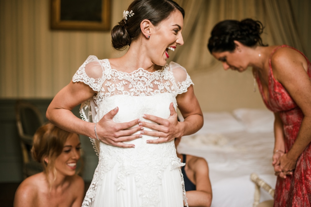 bride getting help from bridesmaids into her wedding dress