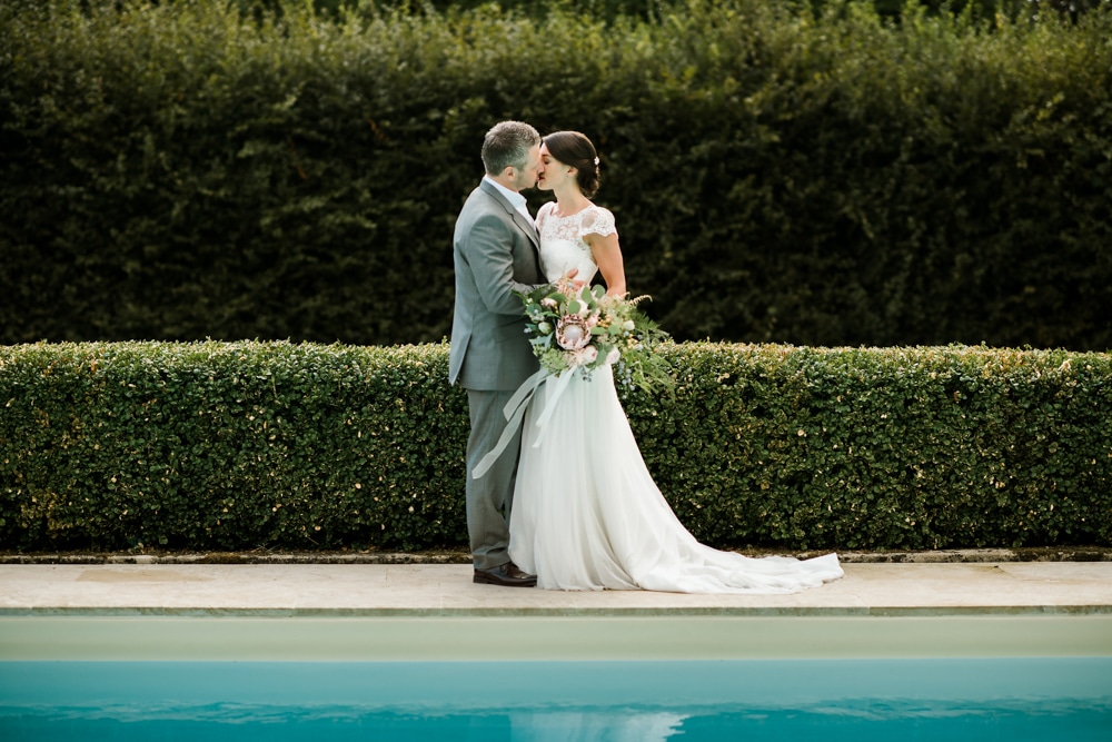 bride and groom kiss by pool