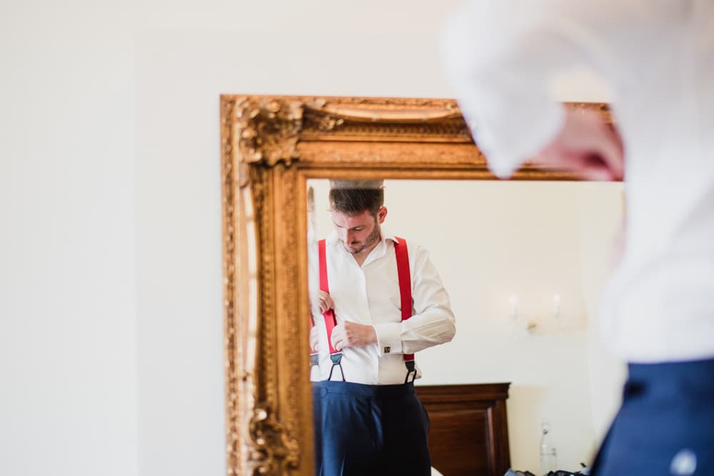 groom wearing red braces getting ready