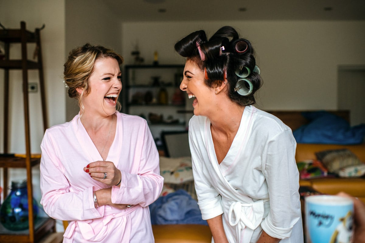 Bride and sister laughing whilst getting ready