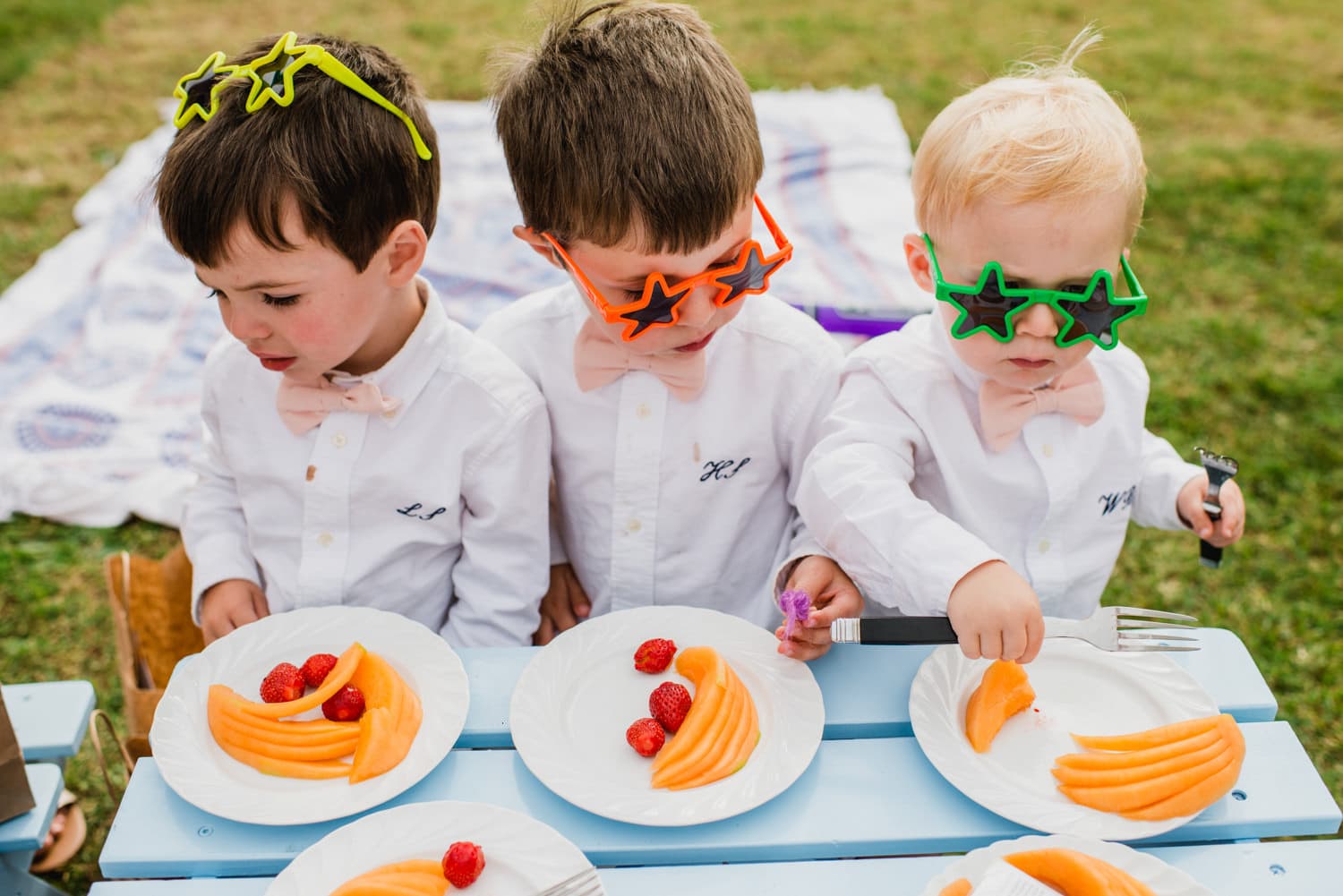 kids at wedding with star glasses sitting on blue picnic bench