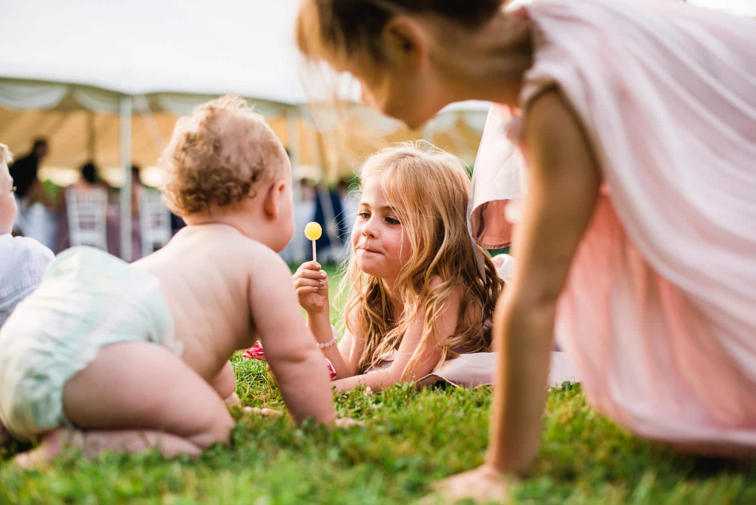 flower girl teasing baby with lollypop